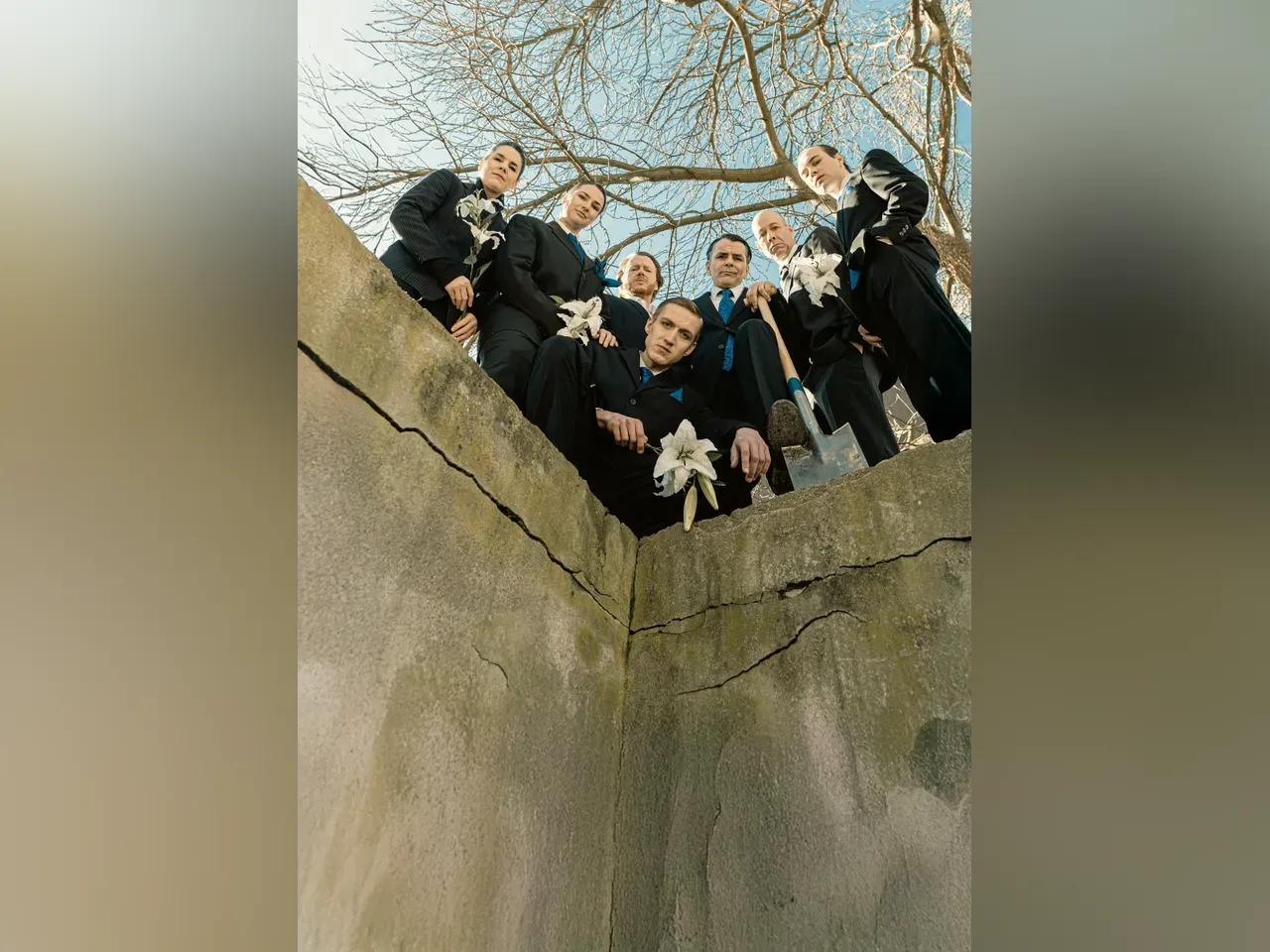 Eine Gruppe von Schauspielern gekleidet in Anzügen schaut von oben herab