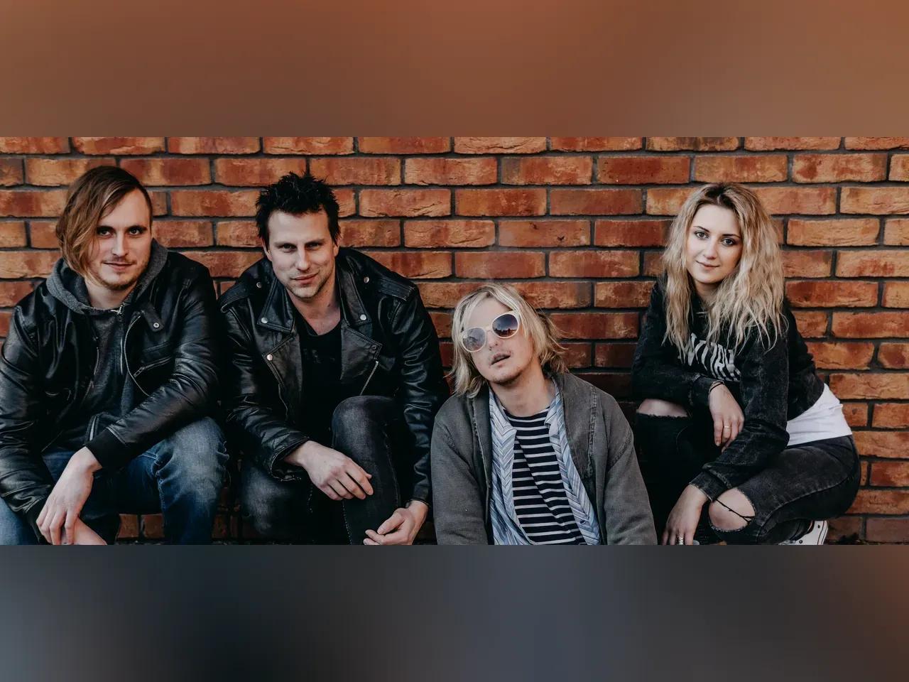 Die 4 Musiker:innen vor einer Ziegelwand