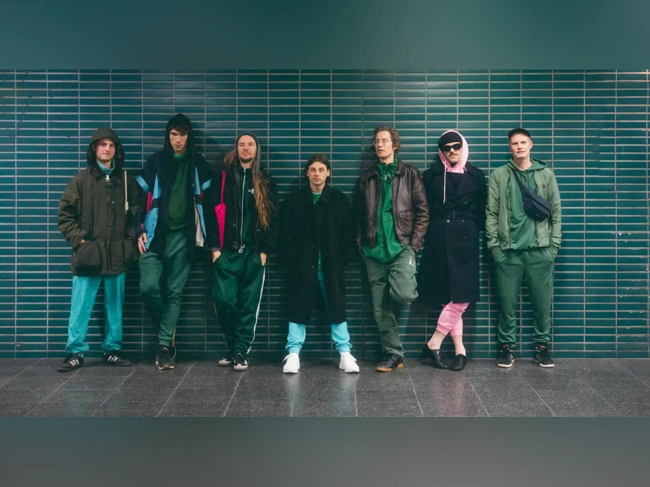 Pressefoto der 7 Musiker vor einer grünen Fliesenwand