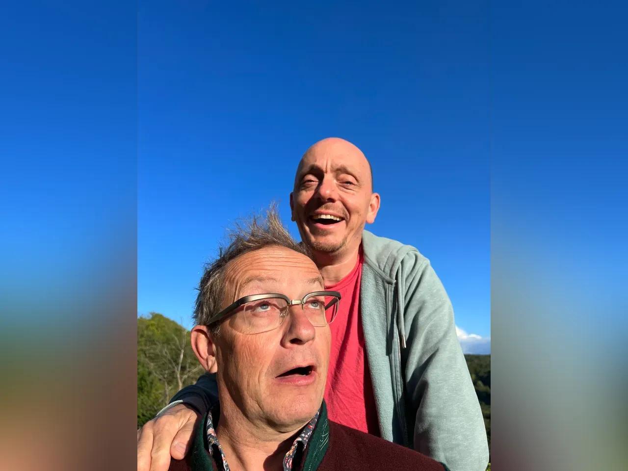 Bernhard Hoëcker und Wigald Boning draußen vor blauem Himmel mit fröhlichen Gesichtern