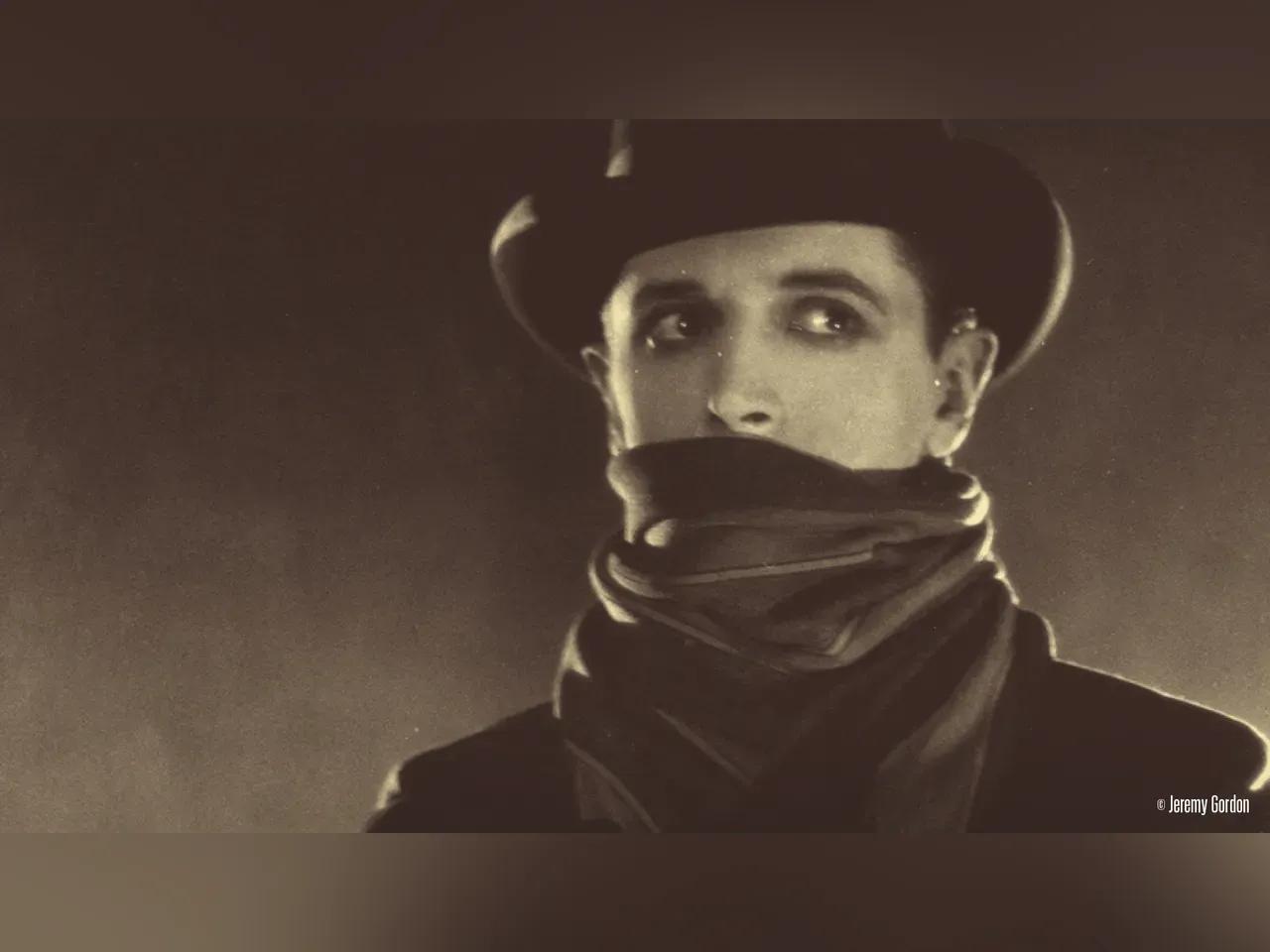 Filmausschnitt auf "The Lodger": Ein Mann mit Hut und halb verdecktem Gesicht blickt verdächtig um sich