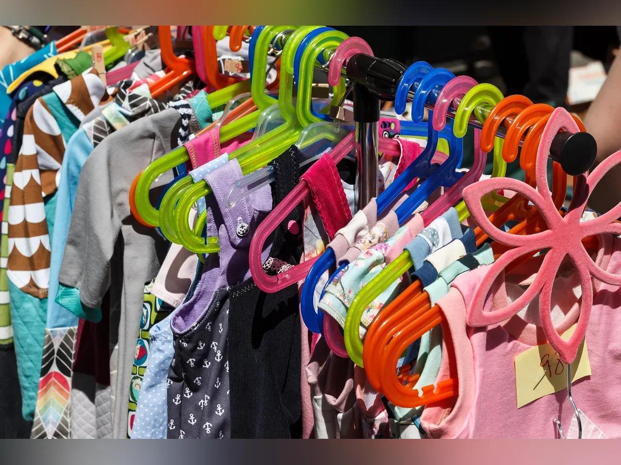 Kindersachen auf einem Flohmarkt hängen auf einem Ständer.