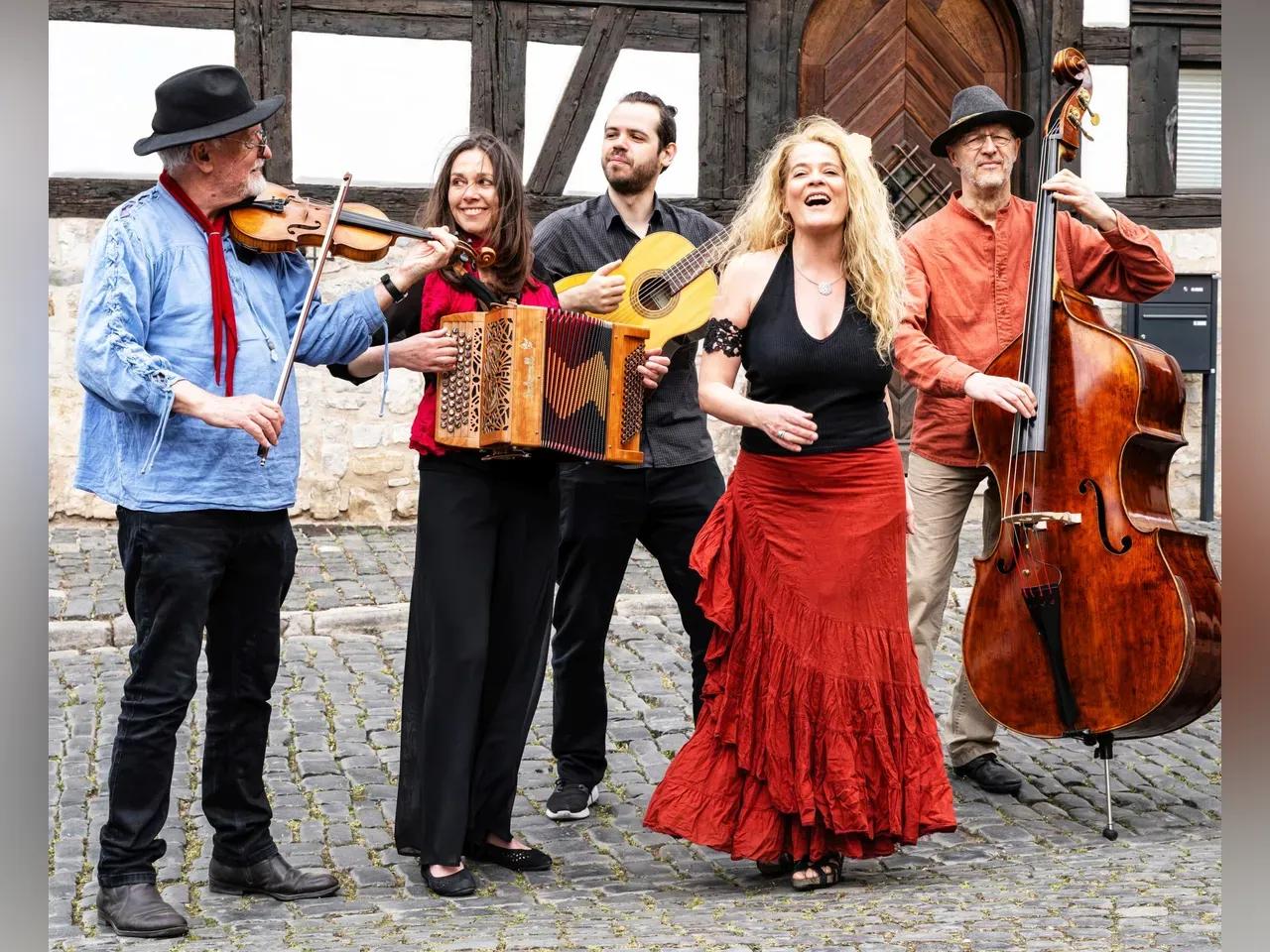 Musiker:innen vob The String Company mit ihren Instrumenten vor einem Fachwerkhaus