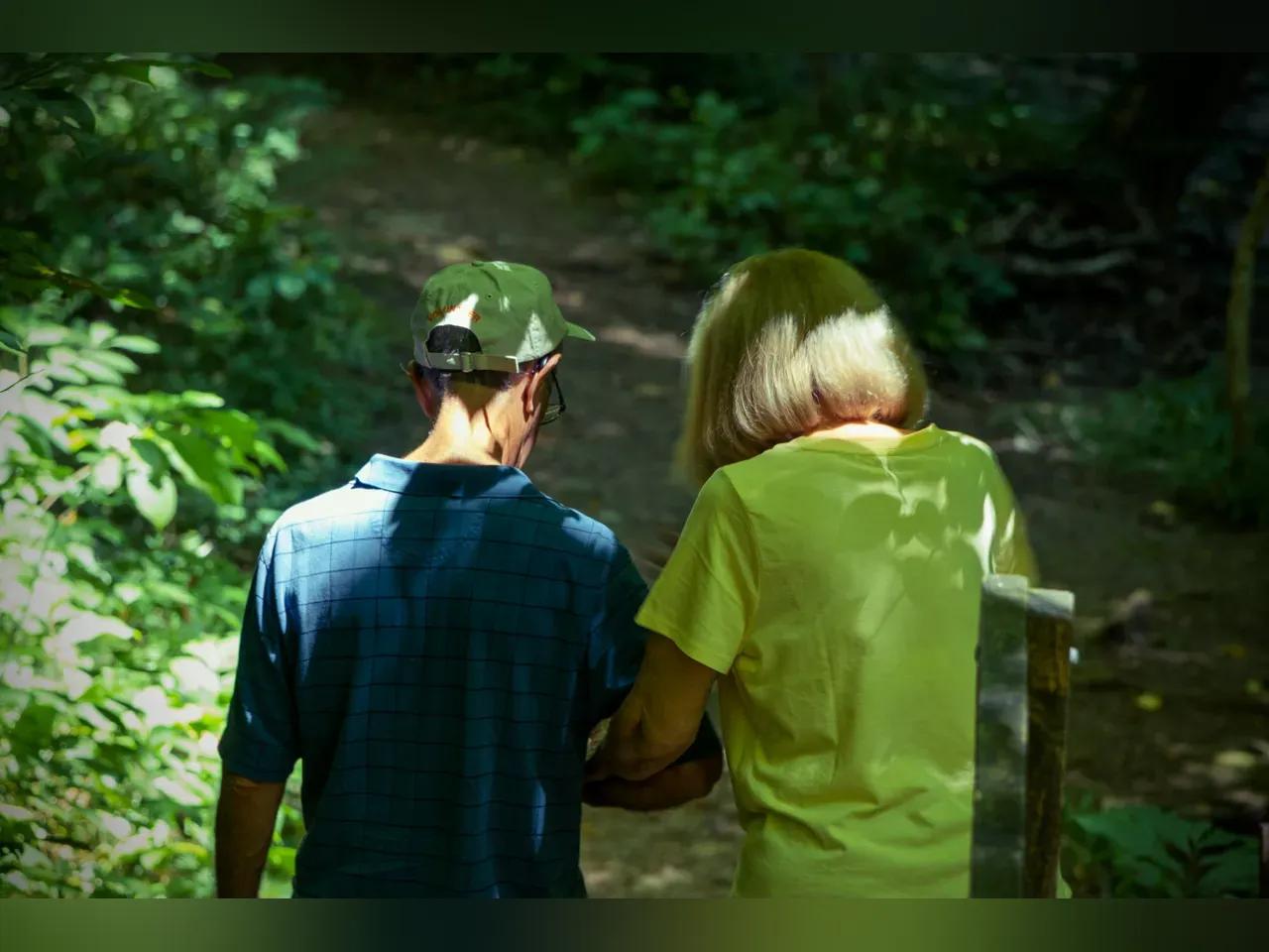 2 Menschen gehen einen Weg entlang und haben die Arme beieinander eingehakt
