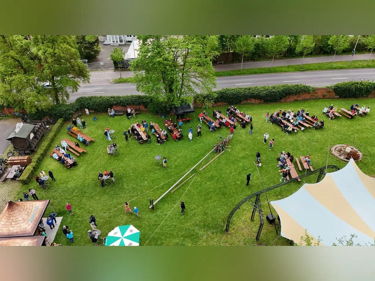 Eine große Wiese, auf der viele Biertischgarnitueren stehen, an denen viele Menschen sitzen. Größere Zelte wurde ebenfalls aufgestellt. 