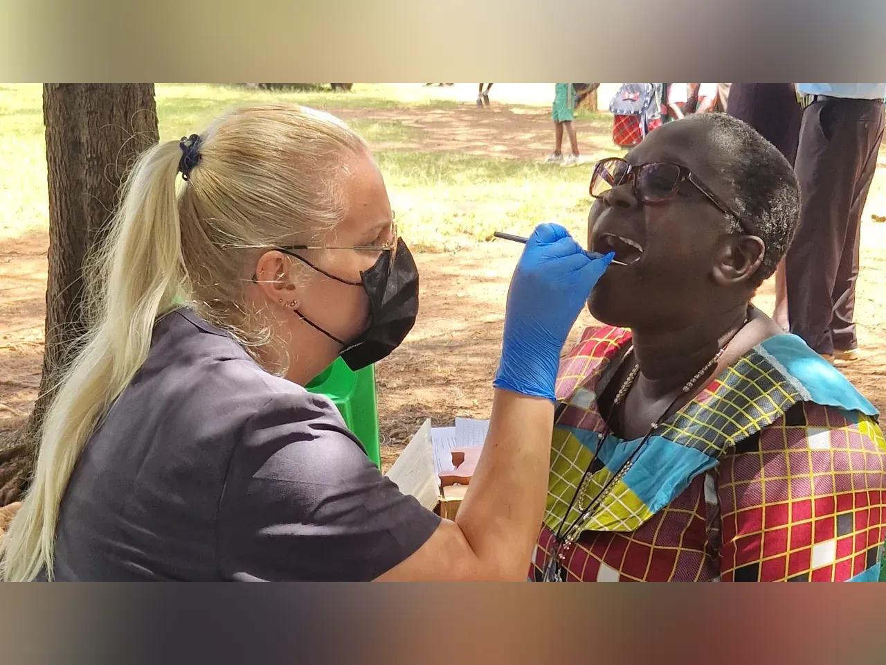 Eine Zahnärztin schaut sich das Gebiss einer afrikanischen Person an